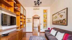 Una sala de estar con televisión de pantalla plana, estanterías de madera, un sofá y obras de arte en las paredes.
