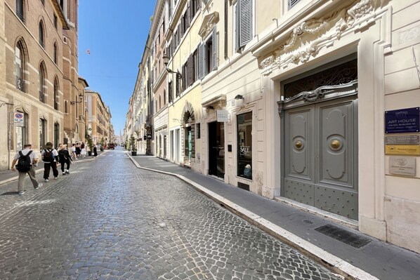 A cobblestone street lined with historic buildings, a closed shop with a signboard, and a plaque indicating an art house. - Studio D'Artista, Stylish Loft in the Heart of Rome (Roma)