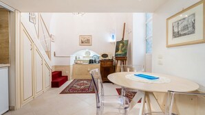 Un espace repas comprenant une table ronde, des chaises, une moquette rouge et un escalier menant à une autre pièce.