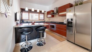 A modern kitchen with a large island, stainless steel appliances, and a bar area with stools. - Cielo Suite, Panoramic View Apt with Jacuzzi (Roma)