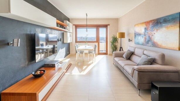 A modern living room with a flat-screen TV, a dining area, a sofa, and a large abstract painting. - Cielo Suite, Panoramic View Apt with Jacuzzi (Roma)