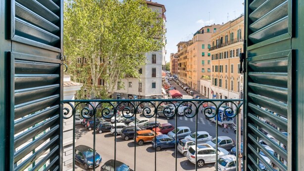 A view through a metal gate of a parking lot with cars, buildings, and a tree. - Elizabeth Penthouse, Charmy Penthouse in Little London (Roma)