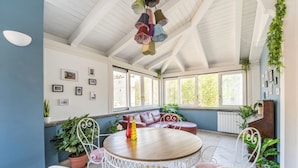 A sunroom with a wooden table, white metal chairs, and a blue wall. - Elizabeth Penthouse, Charmy Penthouse in Little London (Roma)