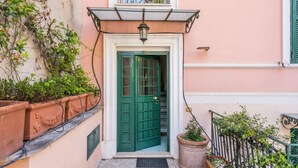 A green door with a white frame, a small window with decorative ironwork, and a potted plant beside the door. - Elizabeth Penthouse, Charmy Penthouse in Little London (Roma)