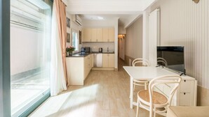 A compact kitchen with a dining area, a TV, and a window with curtains. - Flaminio Garden, Indenpent Apt in Piccola Londra Street with Garden (Roma)