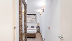 A narrow hallway leading to a bedroom with a bed, a large mirror, and wall-mounted lighting. - Flaminio Garden, Indenpent Apt in Piccola Londra Street with Garden (Roma)