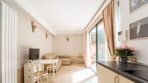 A modern kitchen with a dining area, a sofa, and a window with curtains. - Flaminio Garden, Indenpent Apt in Piccola Londra Street with Garden (Roma)