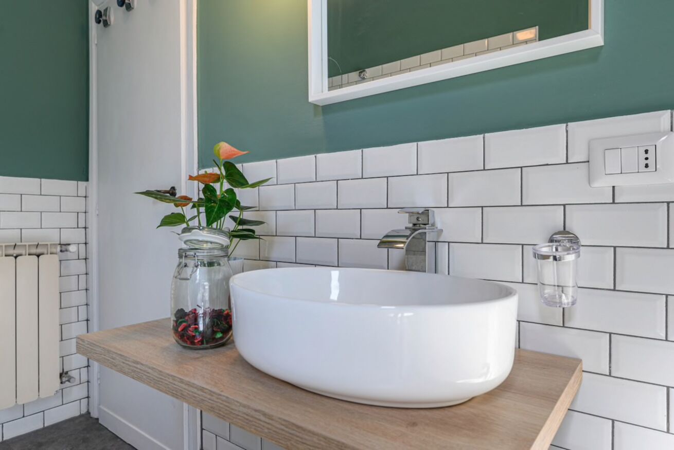 Een badkamer met een wit wastafel, een spiegel en een groene wand.