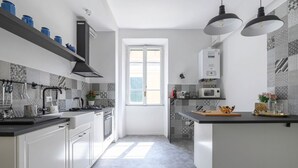 A modern kitchen with white cabinets, a black range hood, a microwave, and a window with blinds. - GLAM 50 - Exclusive Penthouse in the Heart of Rome (Roma)