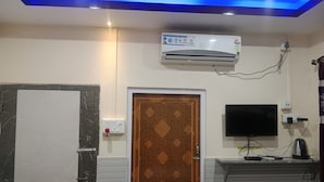 Quarto com porta de mármore, porta estampada, ar-condicionado fixado na parede, televisão de tela plana e régua de tomadas.