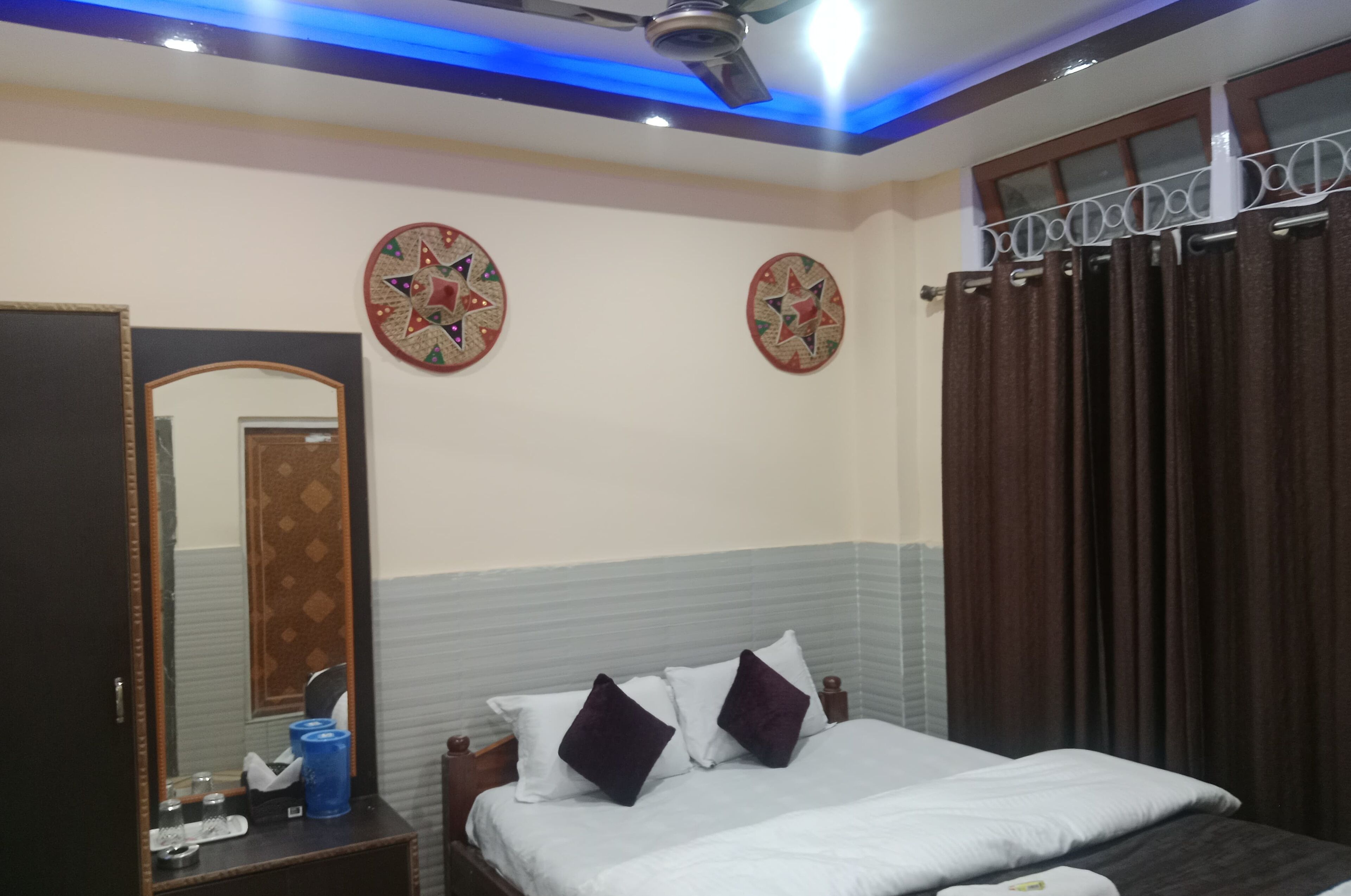 Una habitación de hotel con cama, espejo, mesita de noche y paneles decorativos en la pared.
