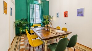 A dining area with a wooden table, yellow and green chairs, a potted plant, and artwork on the walls. - Home of Arts, Concept apt in the Center of Rome (Roma)
