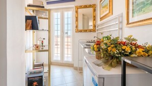 Habitación de hotel con interiores blancos, una estantería, un espejo, un lavabo y una ventana.