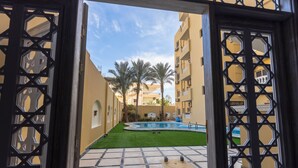 Un patio con piscina, palmeras y suelo de baldosas.