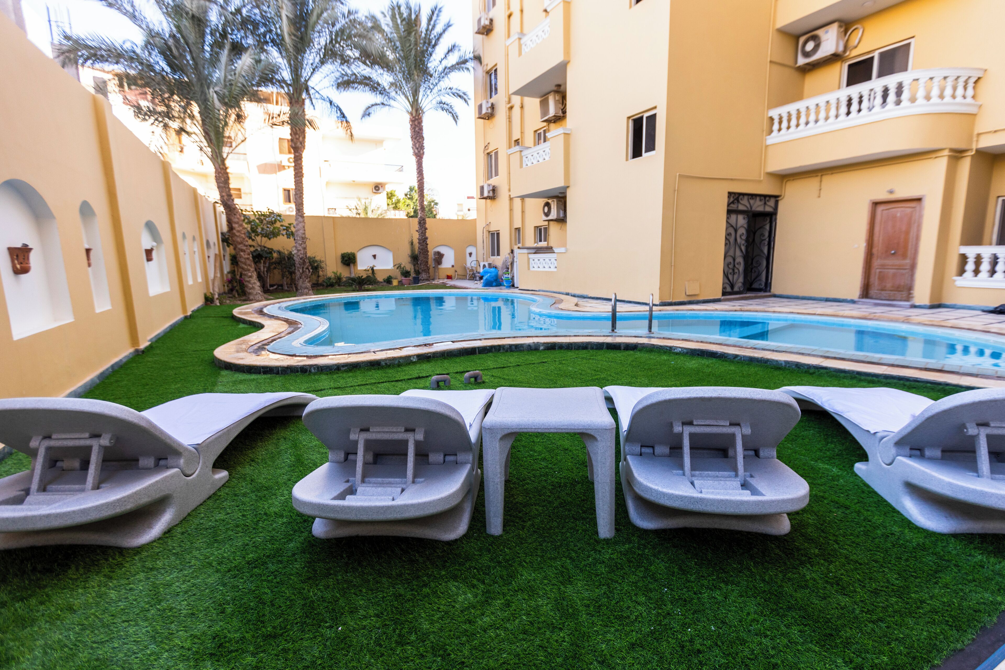 A swimming pool with lounge chairs and palm trees.