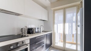 Una cocina moderna con horno empotrado, cafetera y lavamanos.