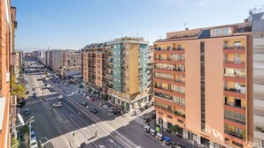 Un edificio de varios pisos con balcones, vista a la calle y cielo despejado.