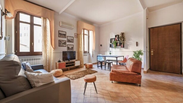 A living room with a sofa, ottoman, TV, dining table, chairs, and a kitchen area. - Re Di Roma Vintage, Flat on the Metro Re di Roma (Roma)