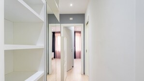 A hallway with a white wardrobe, a door leading to a room with a bed and curtains, and a light-colored floor. - Silver Dream Cornelia, Elegant Apt with Car Park (Roma)