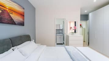 Una camera da letto moderna con un letto, un quadro, un bagno e un angolo cottura.