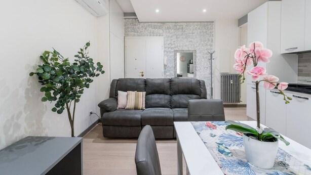 A modern living room with a sofa, a dining table, and a potted orchid. - Silver Dream Cornelia, Elegant Apt with Car Park (Roma)