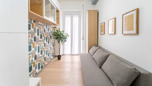 A modern living room with a sofa, a potted plant, and a tiled wall. - Silver Dream Cornelia, Elegant Apt with Car Park (Roma)