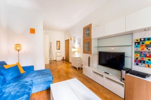 A modern living room with a blue sofa, a flat-screen TV, and a white cabinet. - Sweet Sempione, Cozy Apt Nearby Piazza Sempione (Roma)