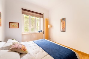A bedroom with a bed, window, artwork, and a lamp. - Sweet Sempione, Cozy Apt Nearby Piazza Sempione (Roma)