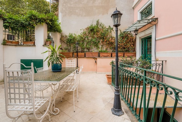 Une terrasse avec une table et des chaises, un lampadaire et une rambarde.