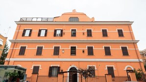 A multi-story building with a symmetrical facade, evenly spaced windows, and a central entrance with an arched doorway. - The Vatican Rest, Elegant Apt Nerby the Basilica (Roma)