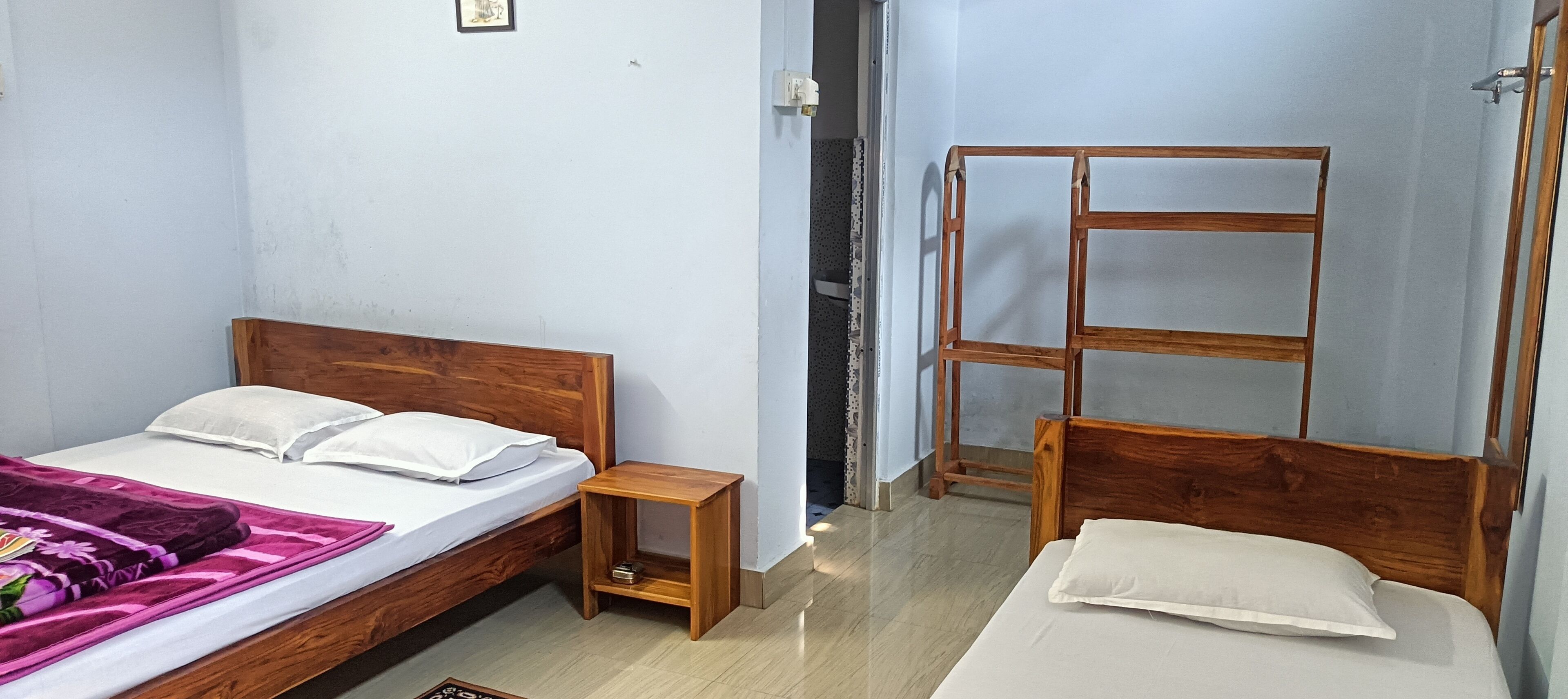 A room with two wooden beds, a small wooden nightstand, and a metal ladder against the wall.