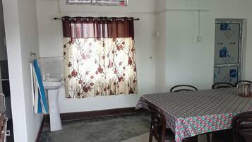 A room with a dining table, chairs, a sink, and a shower curtain.