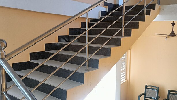 A staircase with metal railings and a ceiling fan. - Sneha Homestay by Roh (Bokakhat)