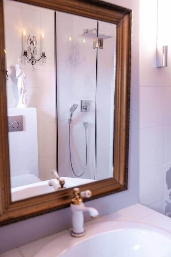 Ein Badezimmer mit einem großen Spiegel, einer Badewanne, einer Dusche und einem WC.