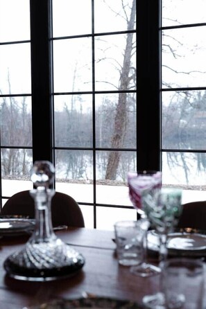 A dining table with a clear view of a snowy landscape through large windows. - Exceptional Alsatian estate with private lake (Rountzenheim-Auenheim)