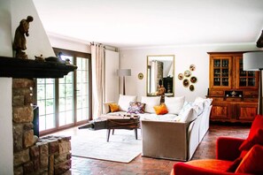 A living room with a fireplace, a sofa, a red armchair, and a wooden cabinet.