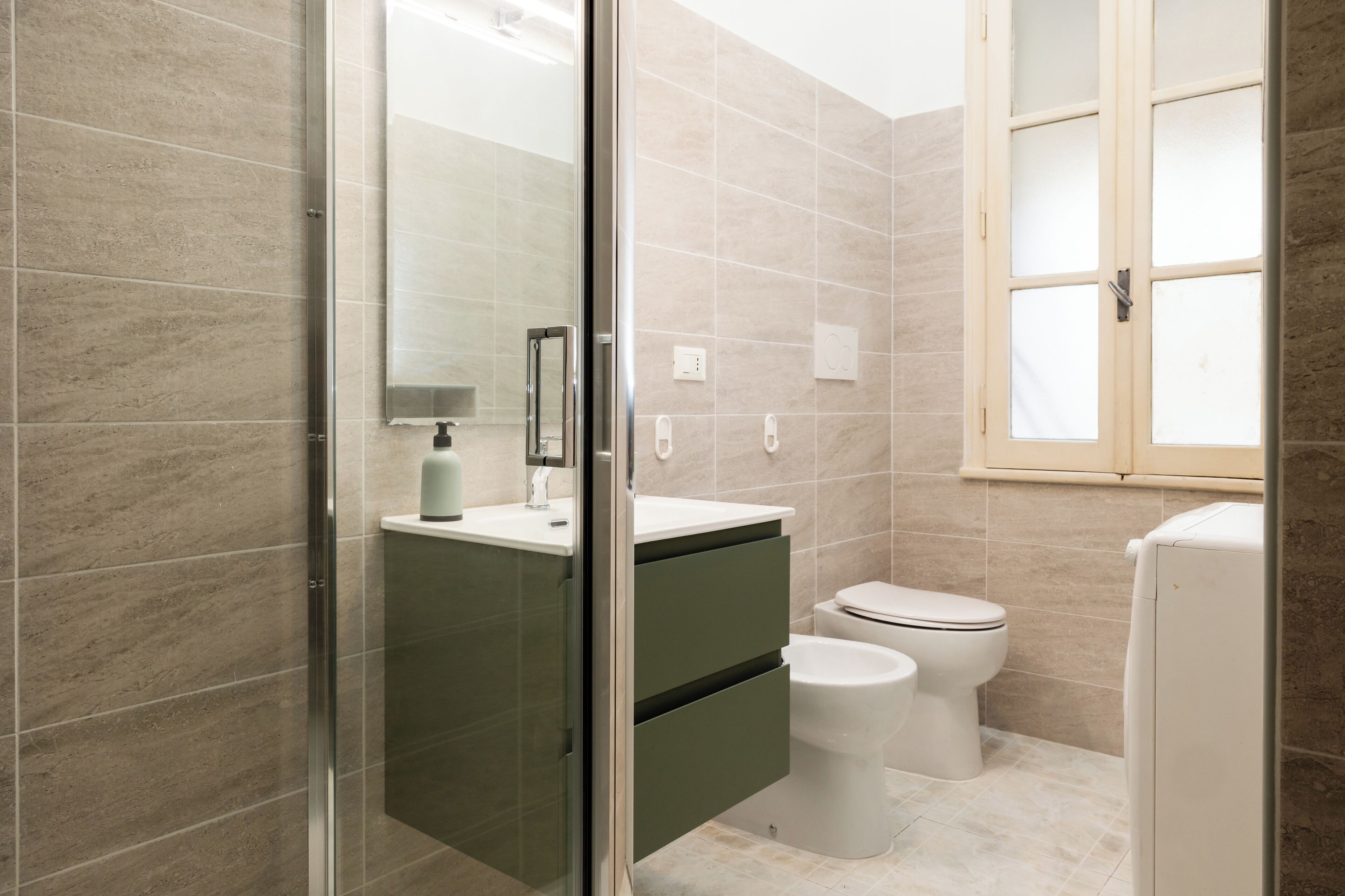 A modern bathroom with a glass shower enclosure, a white sink, and a toilet.