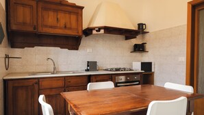 A kitchen with wooden cabinets, a stove, a sink, and a dining table with chairs. - Casa Vic Garbatella in Rome (Rome)