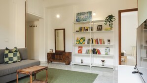 A living room with a sofa, a coffee table, a bookshelf, and a mirror. - Casa Vic Garbatella in Rome (Rome)
