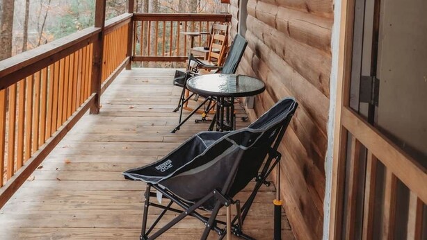 Eine Holzterrasse mit Tisch und Stühlen, einem Klappstuhl und einer Tür.