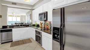 Una cocina moderna con armarios blancos, electrodomésticos de acero inoxidable, un microondas y un refrigerador.