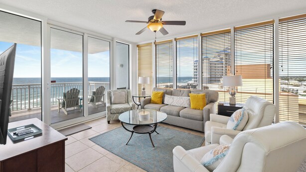 Un balcon avec vue sur l’océan, un ventilateur de plafond et un coin salon avec une table et des chaises.