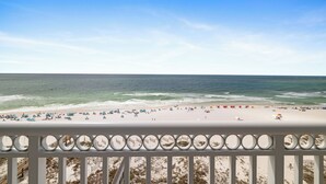 Une plage avec une rambarde au premier plan, une plage de sable et l’océan.