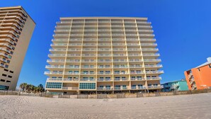 A multi-story hotel with a modern design, featuring balconies on each floor and a prominent glass facade.
