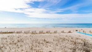 A beach with a fence, a person walking, and a blue line on the sand.