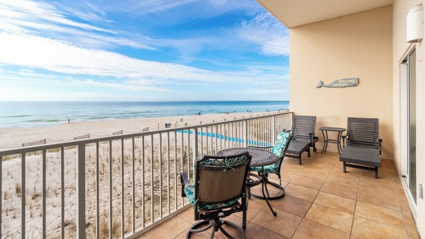 A balcony with a view of the beach, a 'Welcome Aboard' sign, and a pool.