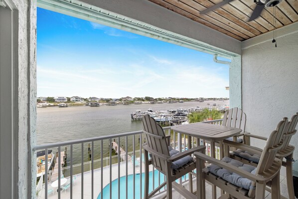 A balcony with a view of a marina, outdoor seating, and a pool.