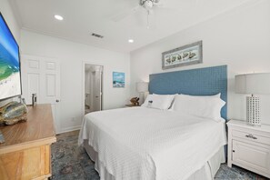 A hotel room with a large bed, a flat-screen TV, a desk with a lamp, and a painting on the wall.