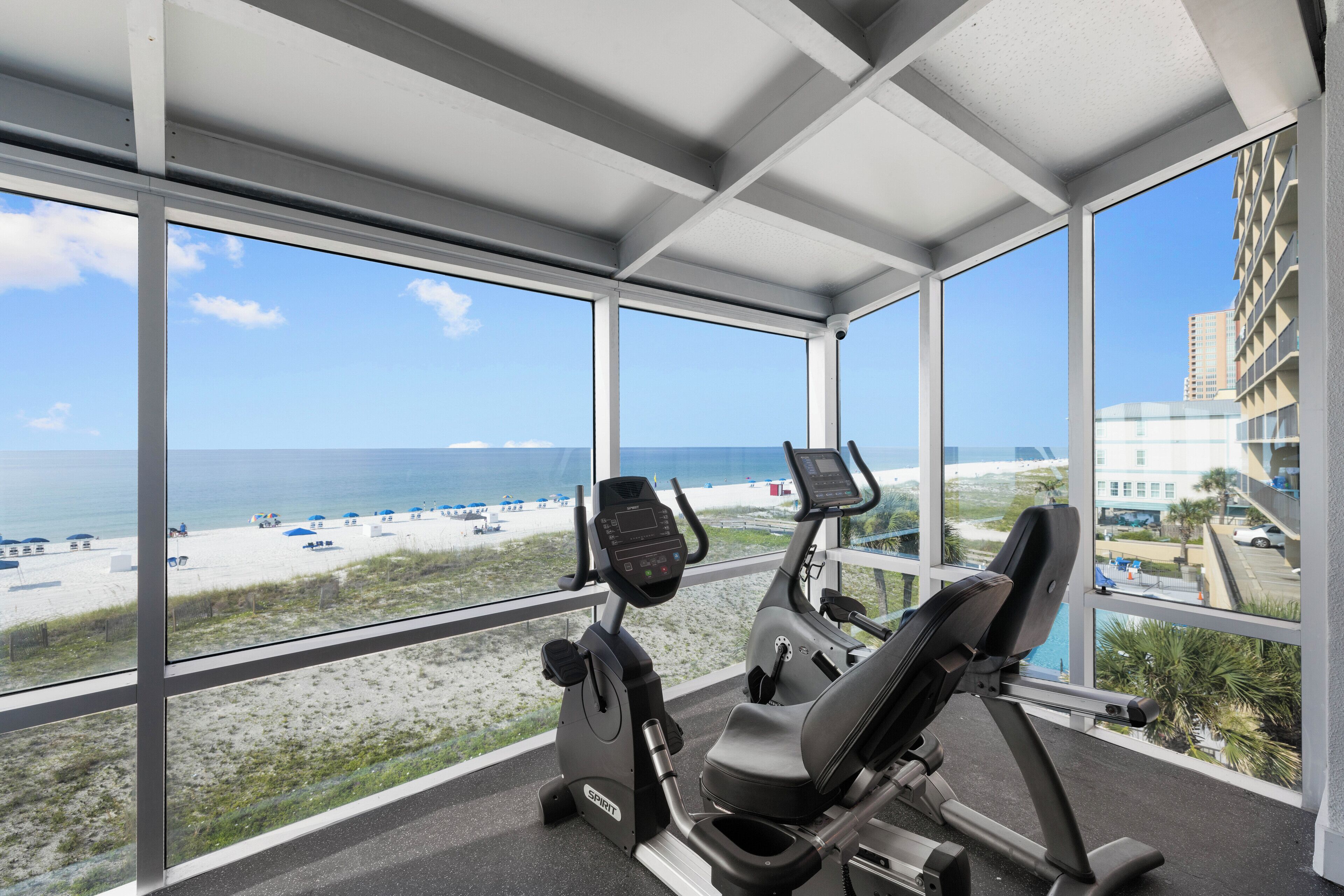 A gym with exercise equipment and a view of the beach and ocean.