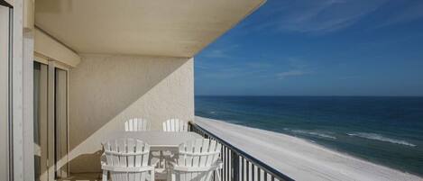 A balcony with a view of the beach and ocean.
